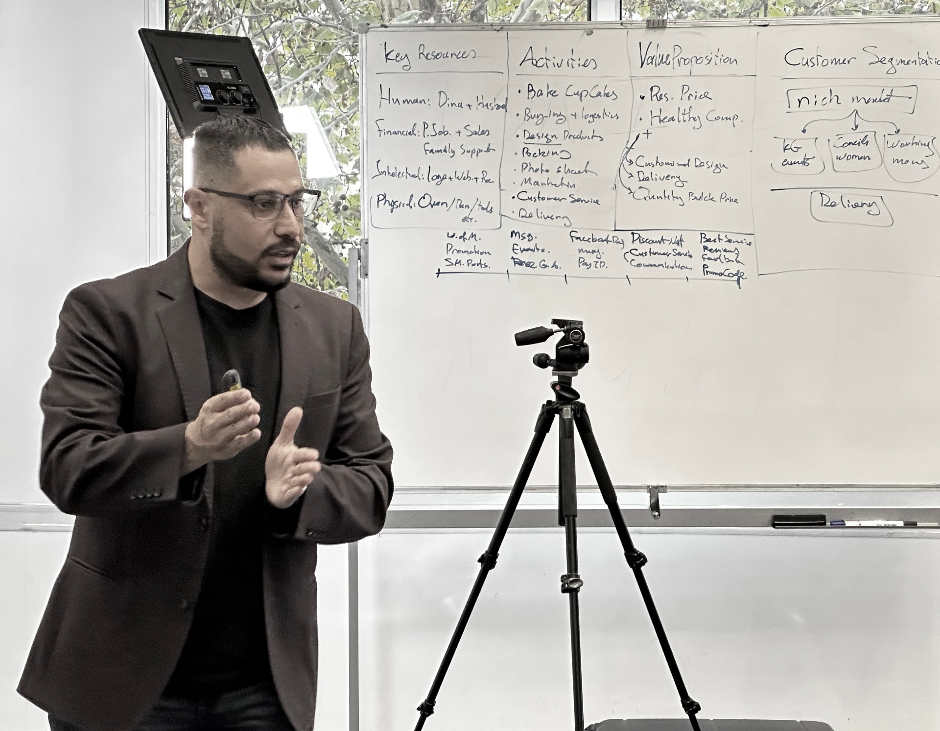 A facilitator explaining business model planning on a whiteboard.