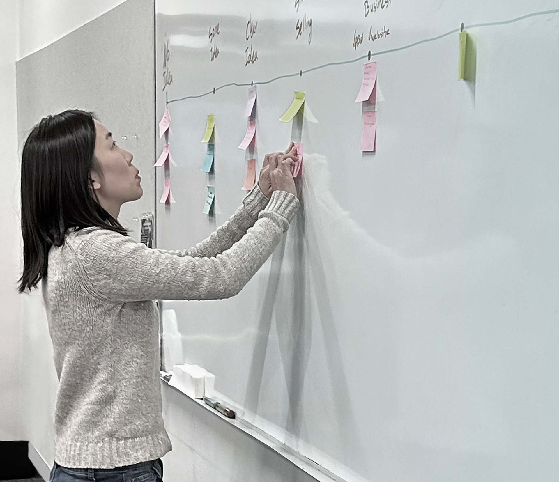 A participant placing notes on a planning board during a workshop.